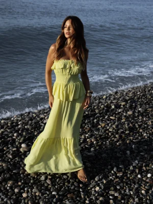“vestido dora kaele longo com babados e lastex” “vestido longo romântico amarelo claro à beira-mar” “detalhe de babados e saia em camadas com caimento fluido”