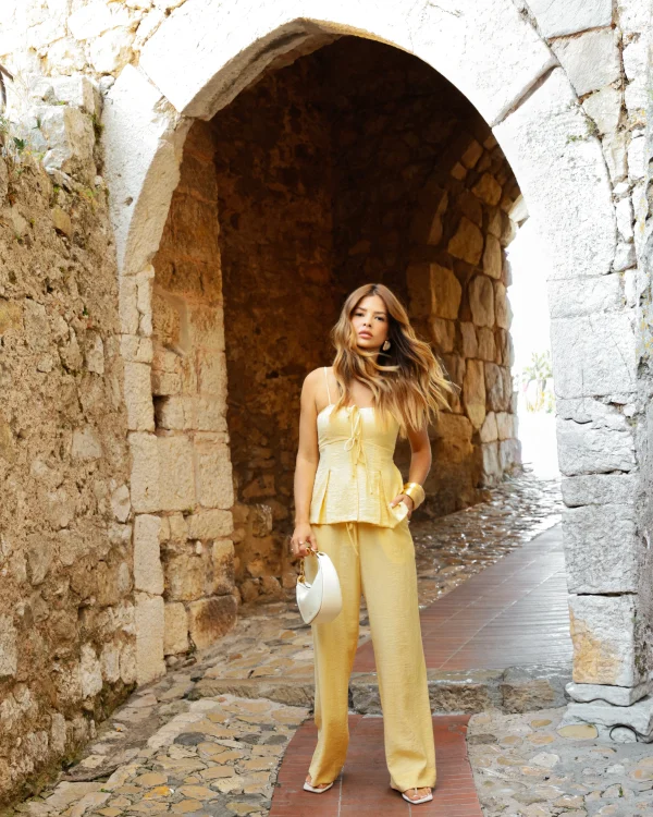 “regata angel kaele amarela com brilho sutil” “regata feminina com alças finas e peplum delicado” “detalhe do tecido acetinado e acabamento elegante”