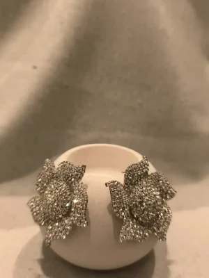 BRINCO FLOR DOURADO STRASS